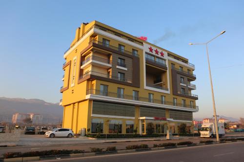 un edificio amarillo con un coche aparcado delante de él en Hotel La Bella, en Alasehir