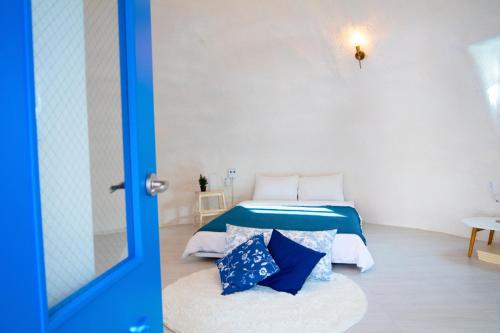a bedroom with a bed with blue and white pillows at All That Water Pension in Gapyeong