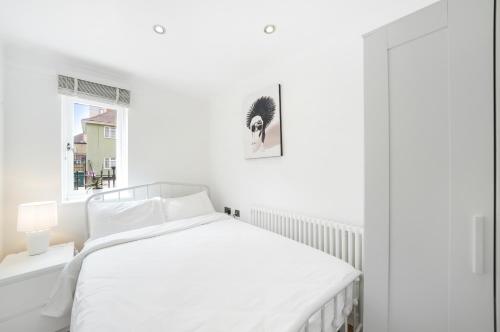 a white bedroom with a white bed and a window at A beautiful stylish 2 Bedroom Apartment -City of London in London