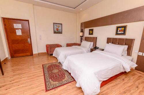 a hotel room with two beds and a door at Hotel One Faisalabad in Faisalabad