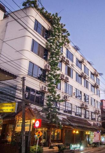 a tall white building with a tree in front of it at Panorama Hotel in Mae Hong Son