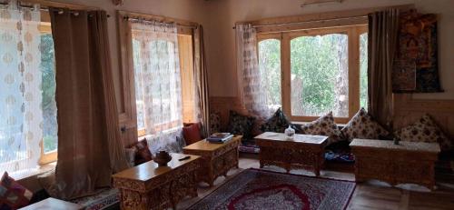 a living room with chairs and tables and windows at KARMA Homestay Sumur Nubra in Nubra