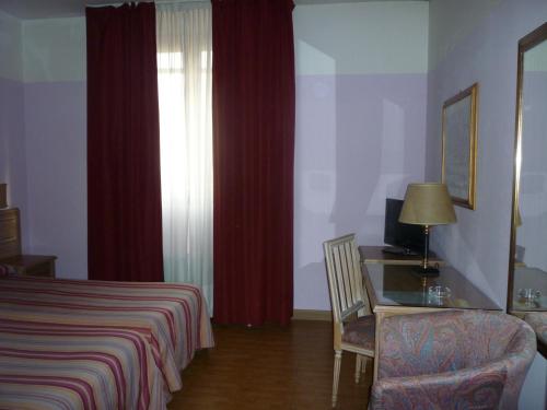 a hotel room with a bed and a desk and a window at Hotel Ascot in Binasco