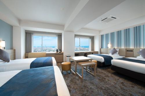 a hotel room with two beds and a desk at Art Hotel Osaka Bay Tower in Osaka