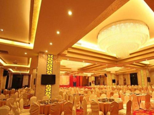a large banquet hall with white tables and chairs at Fortune International Hotel in Xiawutun