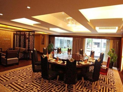 a dining room with a table and chairs on a rug at Fortune International Hotel in Xiawutun