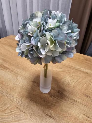a vase filled with blue and white flowers on a table at Apartman FIŠBAH 4 self CHECK-IN, FREE PRIVATE PARKING in Osijek