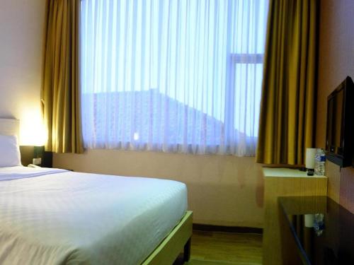 a hotel room with a bed and a large window at Lotus Hotel Subang in Bandung