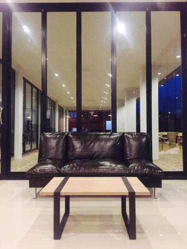 a leather couch in front of a large window at The Nest Hotel Phichit in Ban Khlong Khachen