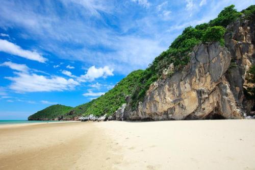 a sandy beach with a large rock wall at Villa Gris Pranburi in Pran Buri