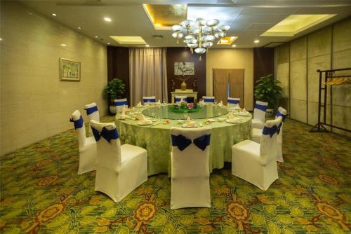 a dining room with a table and white chairs at Huangshan International Hotel in Huangshan