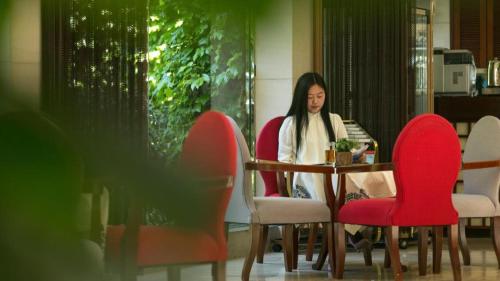 a woman sitting at a table with red chairs at Huangshan International Hotel in Huangshan