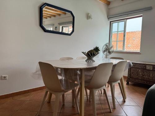a dining room table with chairs and a mirror at Porto Covo / Costa Alentejana in Porto Covo