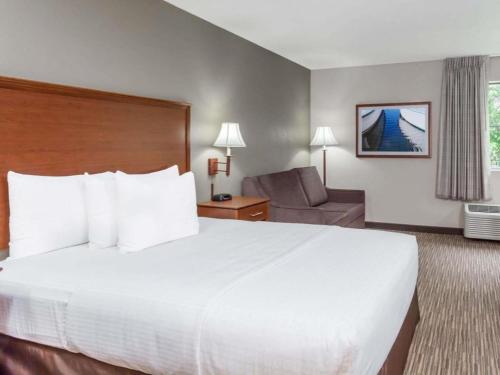 a hotel room with a large white bed and a chair at Days Inn Springfield South in Springfield