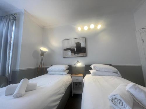two beds in a small room with white sheets at Central Hotel in Norwich