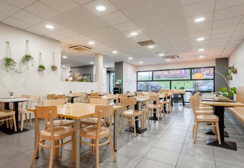 une salle à manger avec des tables et des chaises en bois dans l'établissement B&B HOTEL Maubeuge-Louvroil, à Louvroil