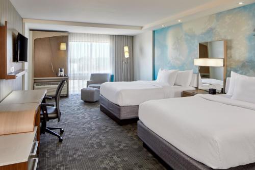 a hotel room with two beds and a desk at Courtyard by Marriott Atlanta Lithia Springs in Lithia Springs