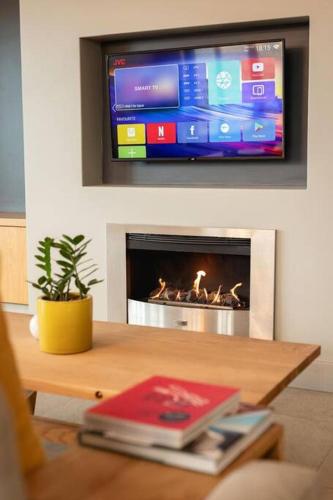 a living room with a fireplace with a tv above it at Ocean Family Deluxe, Hermanus Waterfront - Apt 2 in Hermanus