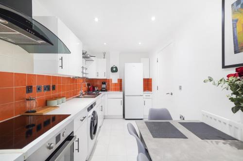 a kitchen with white appliances and orange and white tiles at A beautiful stylish 2 Bedroom Apartment -City of London in London