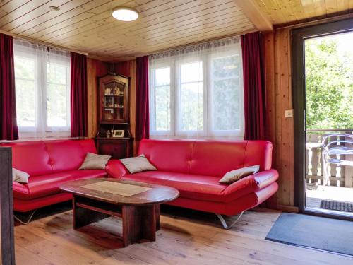 a living room with a red couch and a table at Chalet Zur Säge by Interhome in Albinen