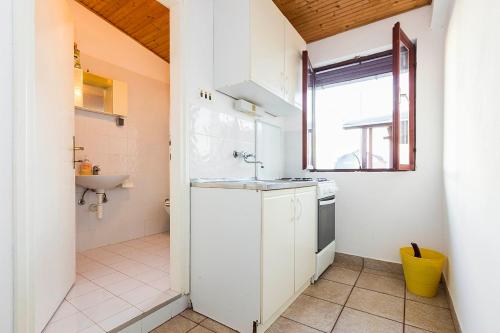a small white kitchen with a sink and a window at Apartments Draga in Sukošan