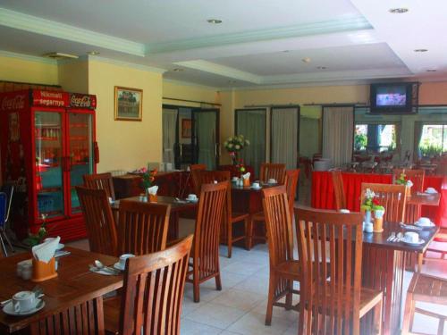 a restaurant with wooden tables and chairs and a television at Jimbarwana Hotel in Negara