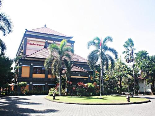 a large building with palm trees in front of it at Jimbarwana Hotel in Negara