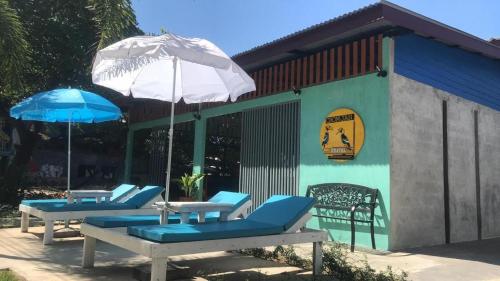 a group of chairs and umbrellas in front of a building at Chomjan Hostel in Ko Phayam