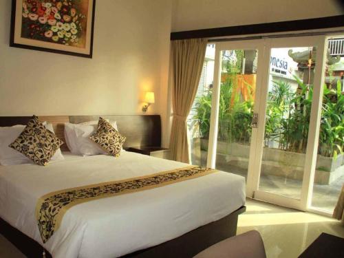 sypialnia z łóżkiem i dużym oknem w obiekcie Losari Sunset Hotel w mieście Kuta