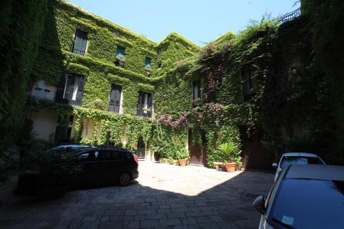 a building covered in ivy with cars parked in front at Palazzo Rollo in Lecce