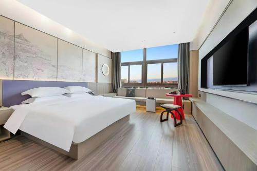 a hotel room with a large bed and a flat screen tv at New Century Mansion Hotel Cixi Guanhaiwei in Cixi