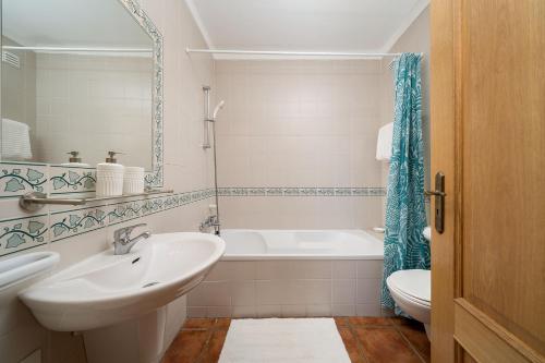 a bathroom with a sink and a tub and a toilet at Albufeira Palm Tree With Pool by Homing in Albufeira
