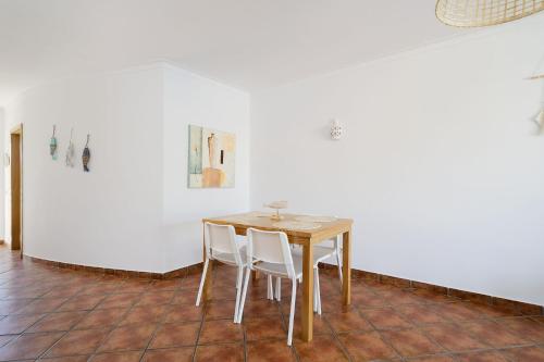 a table and chairs in a room with a white wall at Albufeira Palm Tree With Pool by Homing in Albufeira