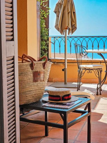 a balcony with a table and a chair and an umbrella at Hôtel La Pérouse Nice Baie des Anges in Nice
