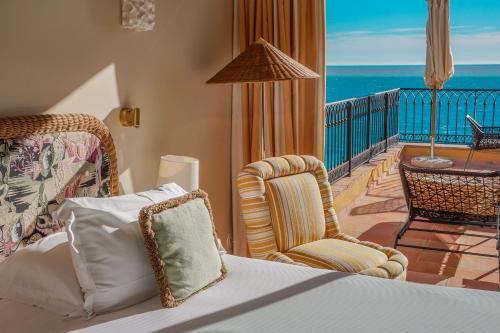 a bedroom with a bed and a balcony with the ocean at Hôtel La Pérouse Nice Baie des Anges in Nice