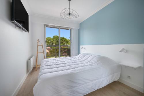 une chambre blanche avec un grand lit et une fenêtre dans l'établissement Séjour vue mer pour 4 - 20m plage de la Baule, à La Baule
