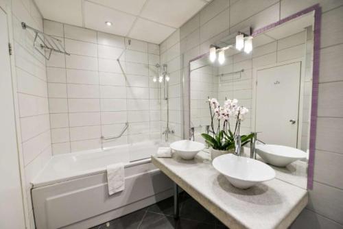 a white bathroom with two sinks and a tub and a tubermott at Art Plaza Hotel in Sofia
