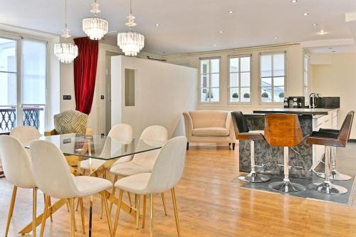 une salle à manger avec une table en verre et des chaises blanches dans l'établissement Appartement prestigieux et lumineux de 150m2 - II, à Paris