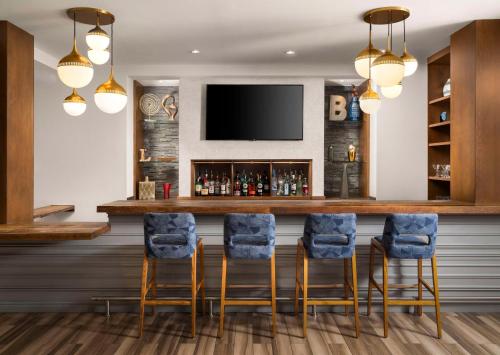 a bar in a hotel room with chairs and a tv at Homewood Suites by Hilton Boston Brookline-Longwood Medical in Brookline