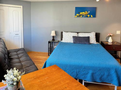 ein Schlafzimmer mit einem blauen Bett und einem Sofa in der Unterkunft Spacious Studio w/ Parking, beach/mall/park in Honolulu