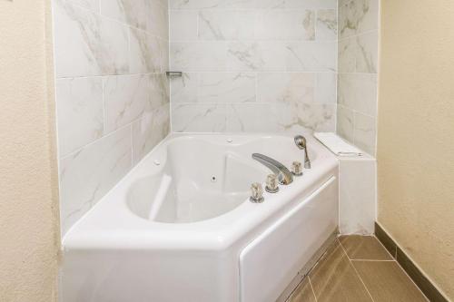 a white bath tub in a bathroom with white tiles at Comfort Inn Detroit Downtown in Detroit