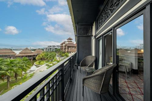 a balcony with two chairs and a view of the ocean at DoubleTree by Hilton Putrajaya Lakeside in Putrajaya
