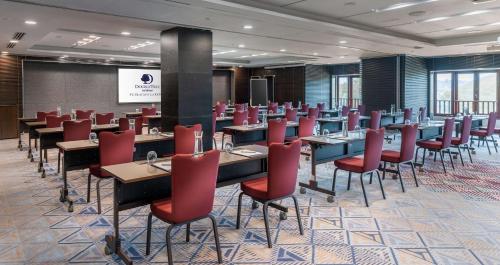 a conference room with tables and red chairs at DoubleTree by Hilton Putrajaya Lakeside in Putrajaya