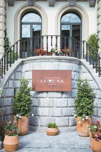 a sign on a building with potted plants at Hotel Luruna Palacio Larrinaga in Mundaka