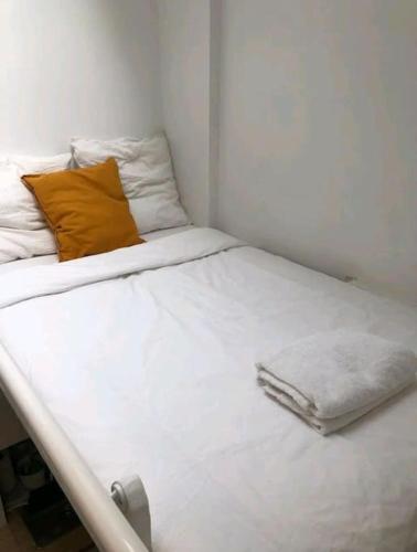 - un lit blanc avec un oreiller orange dans l'établissement au COEUR de Paris Joli Nid équipé calme clair Ascenseur AC, à Paris
