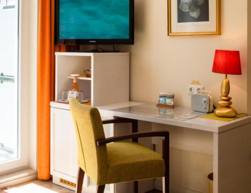 a desk with a chair and a television on a wall at Hotel Garni Inselparadies Zingst in Zingst