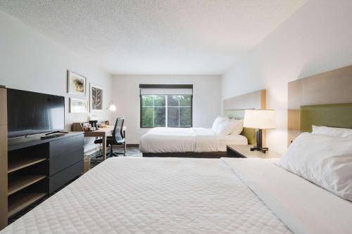 a hotel room with two beds and a desk at Country Inn & Suites by Radisson, Queensbury - Lake George , NY in Lake George
