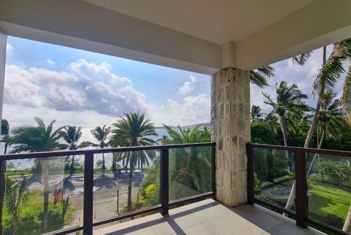 a balcony with a view of the ocean and palm trees at Ramada Suites By Wyndham Seafront Coral Coast in Korotogo