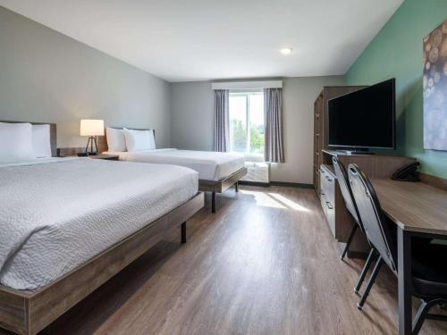 a hotel room with a bed and a flat screen tv at ECHO Suites Extended Stay by Wyndham Spartanburg in Spartanburg