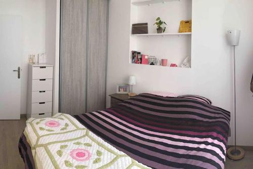 une chambre avec un lit avec une couverture rayée dans l'établissement Cozy Flat, 5 mins from metro, 1 bedroom, à Paris
